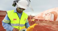 worker in hard hat and yellow vest on field of red bauxite