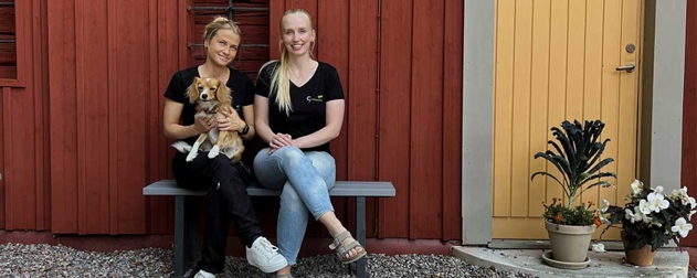 two women sitting on a bench with a dog