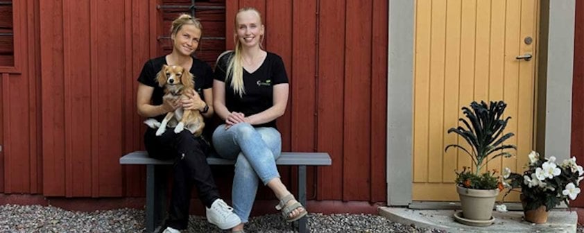 two women sitting on a bench with a dog