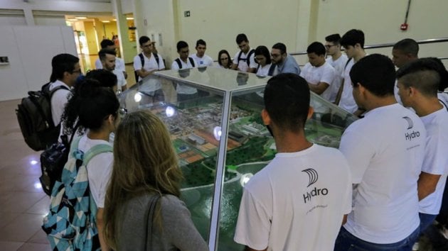 Young people wearing white Hydro t-shirts, observing a development scale model