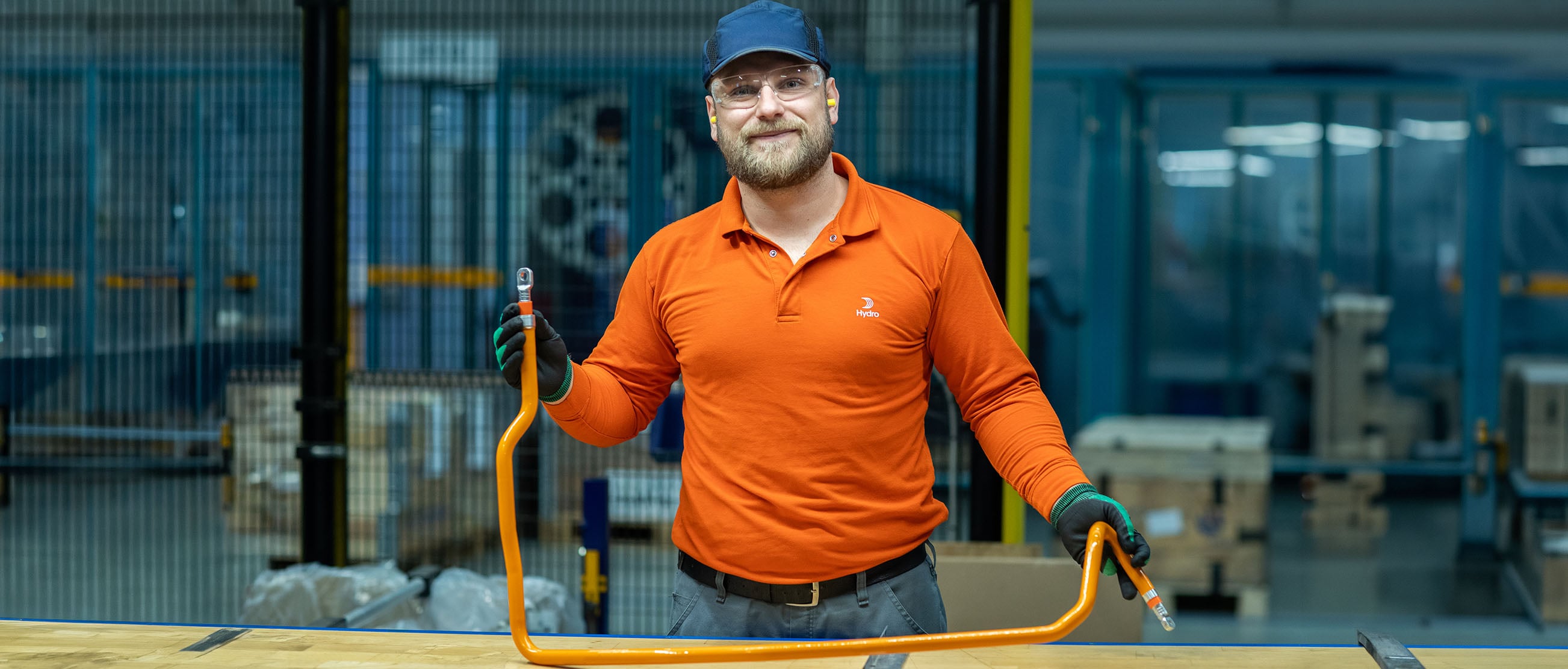 A man wearing a hat and gloves holding a an aluminium busbar