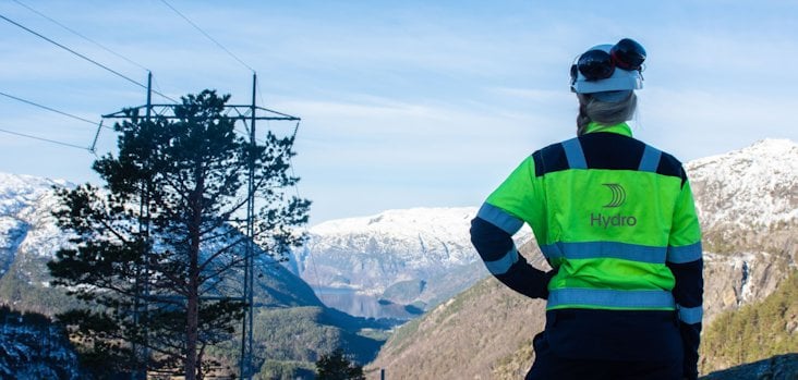 Worker in Hydro gear, looking out over mountainous winter landscape