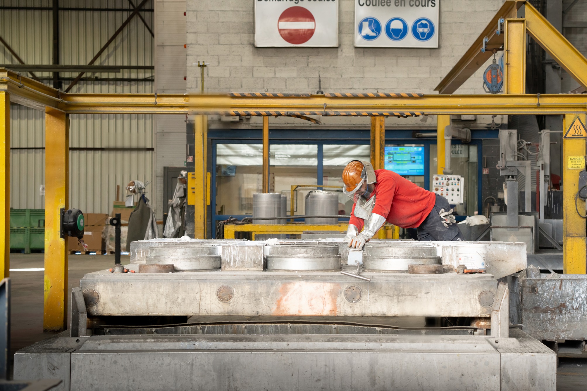 a man in a red shirt working on a large piece of metal