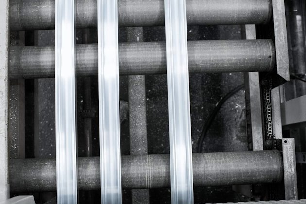 Overhead image of three pieces of extruded aluminum on rollers