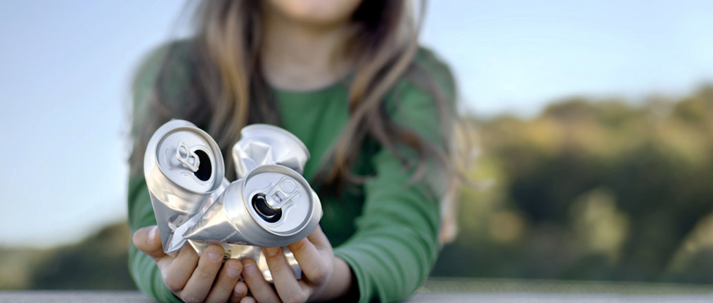 Girl holding crumpled aluminum cans