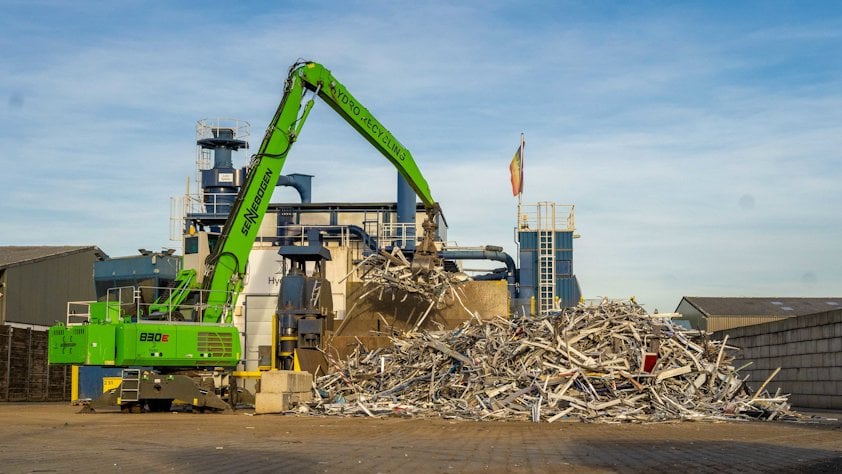 A crane lifting a pile of aluminium scrap