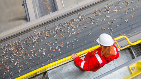Arbetare som observerar transportband med burkar avsedda för återvinning