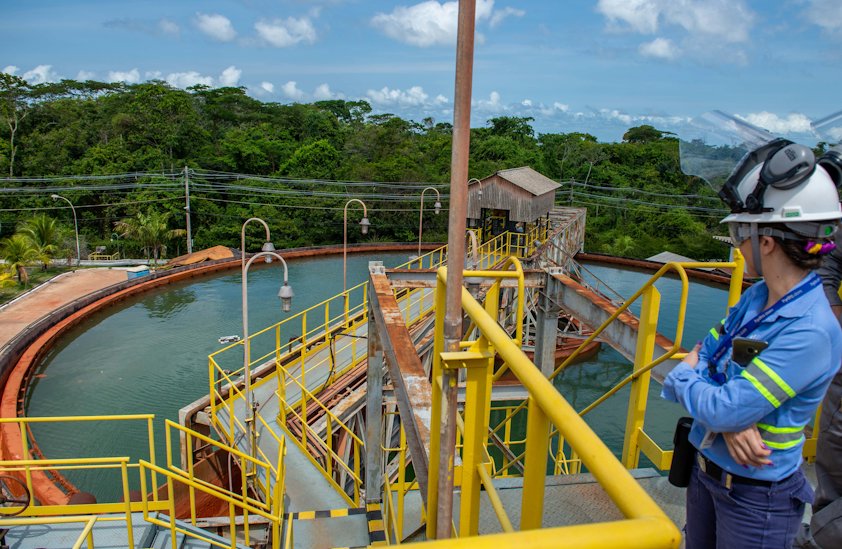 a woman wearing a helmet and standing on a bridge over a water basin