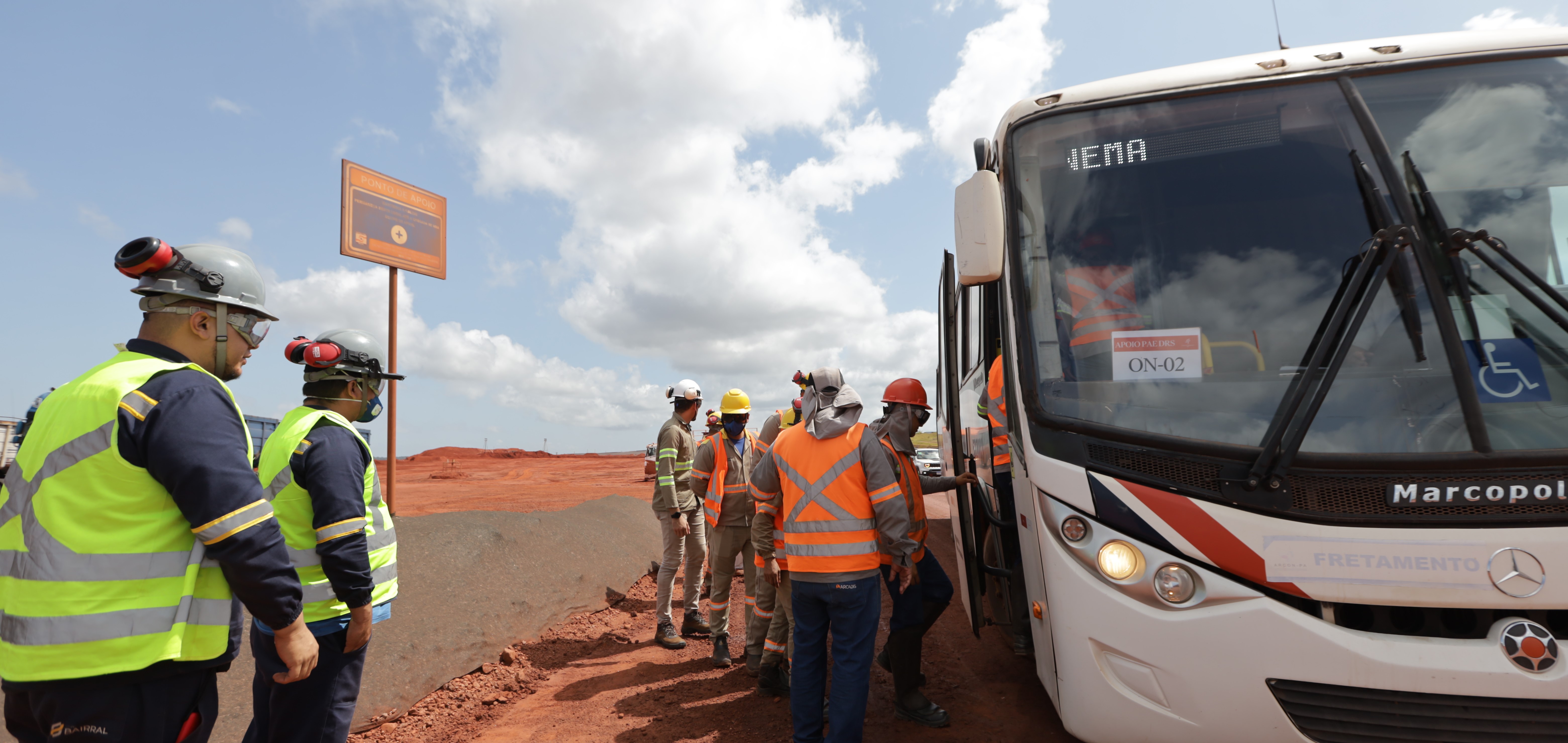 a group of people in safety vests standing next to a bus