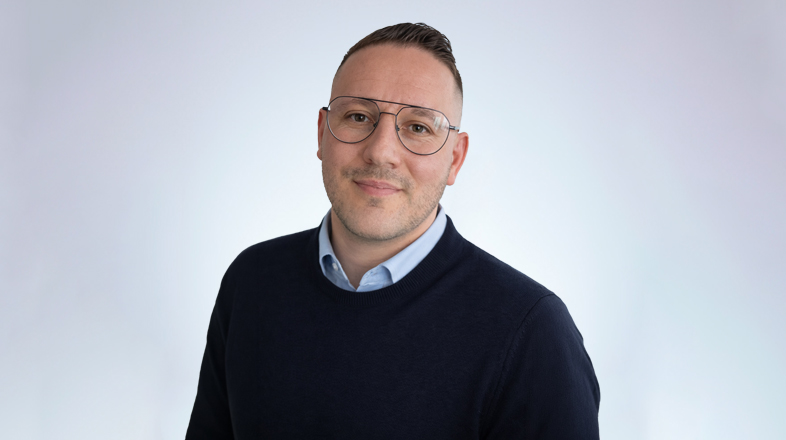a man wearing glasses and a blue sweater