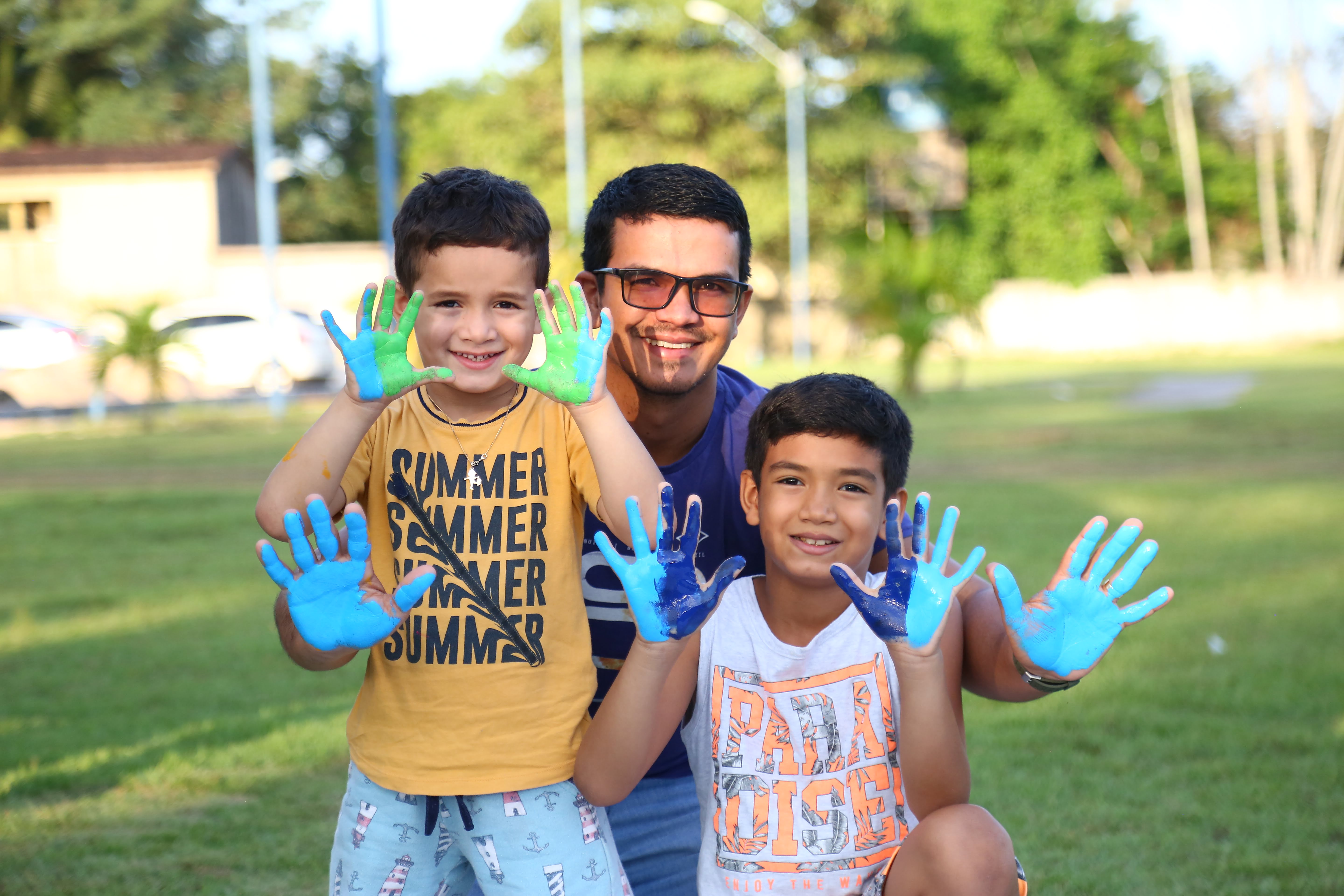 a person and two boys holding up blue and green plastic gloves