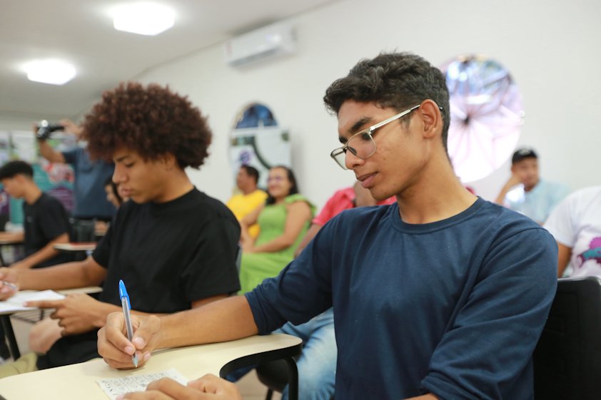 a man and a woman sitting at a table writing on paper