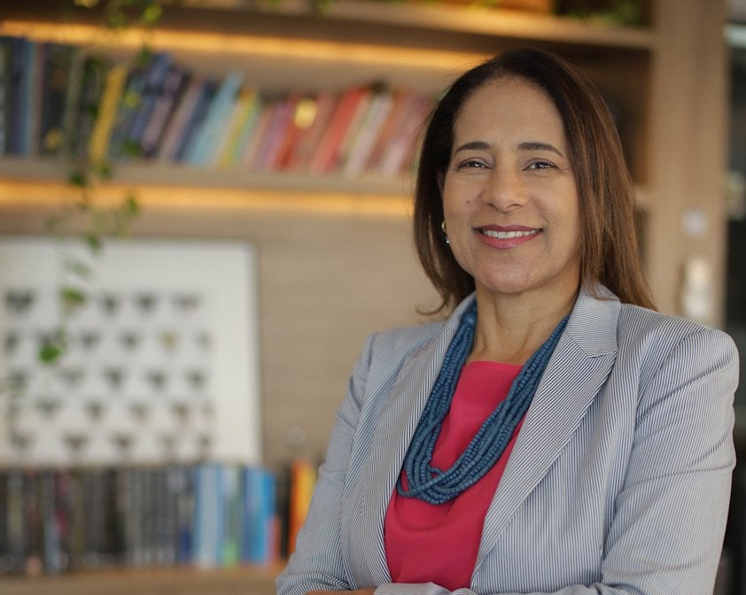 a woman smiling in front of a book shelf