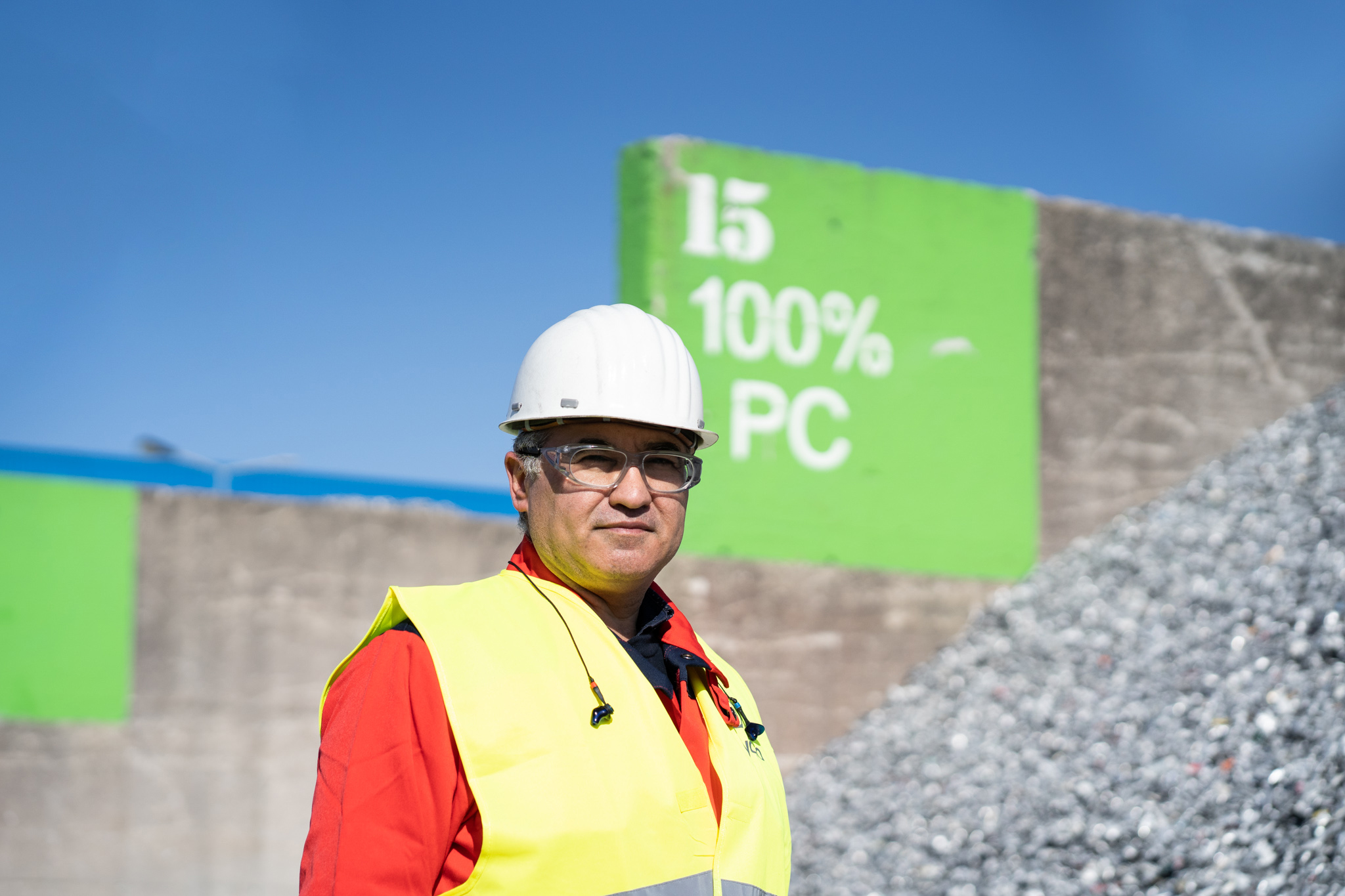 a man wearing a hard hat and glasses standing in front of a sign