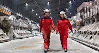 a man and woman wearing helmets and walking in a warehouse