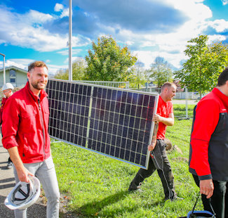Hydro Mitarbeiter tragen Solarpanel für Solarzaun in Offenburg