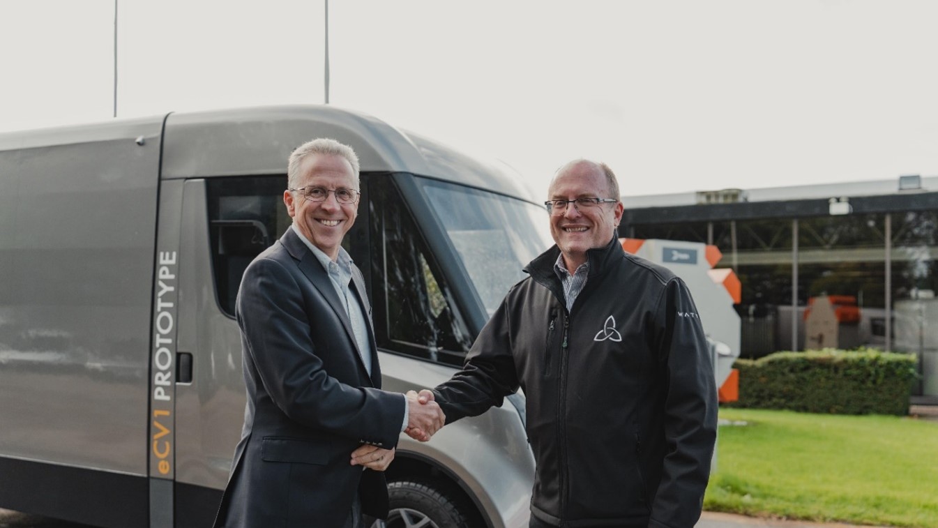 two men in suits standing in front of a van