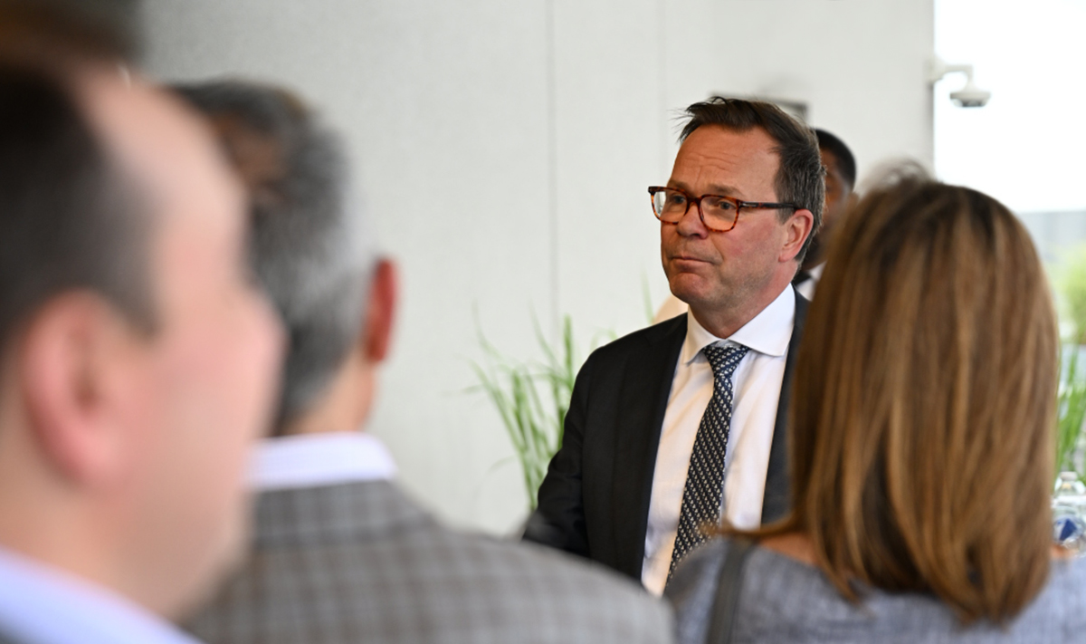 a person in a suit and tie talking to a group of people