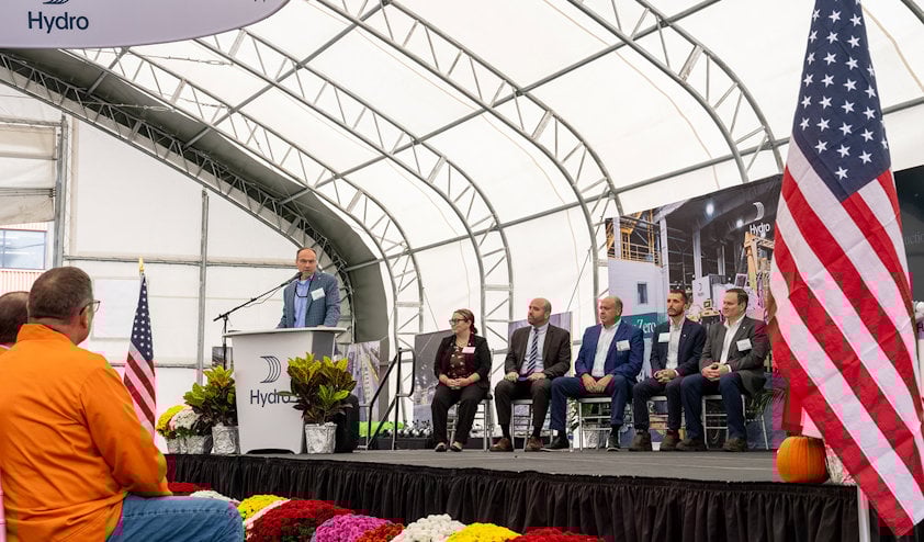 a group of people sitting on a stage with flags