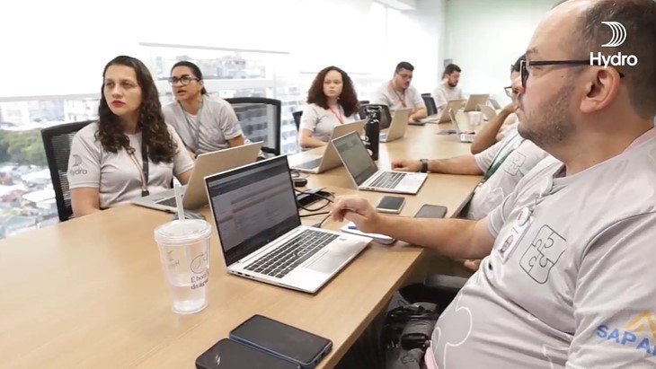 a group of people sitting at a table with laptops
