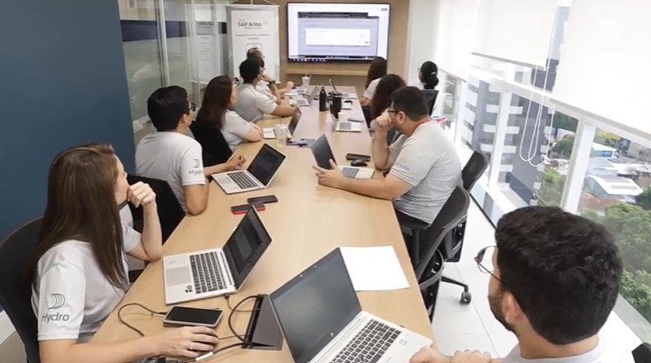 a group of people sitting around a table with laptops