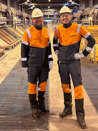 a couple of men in safety gear standing on a factory floor