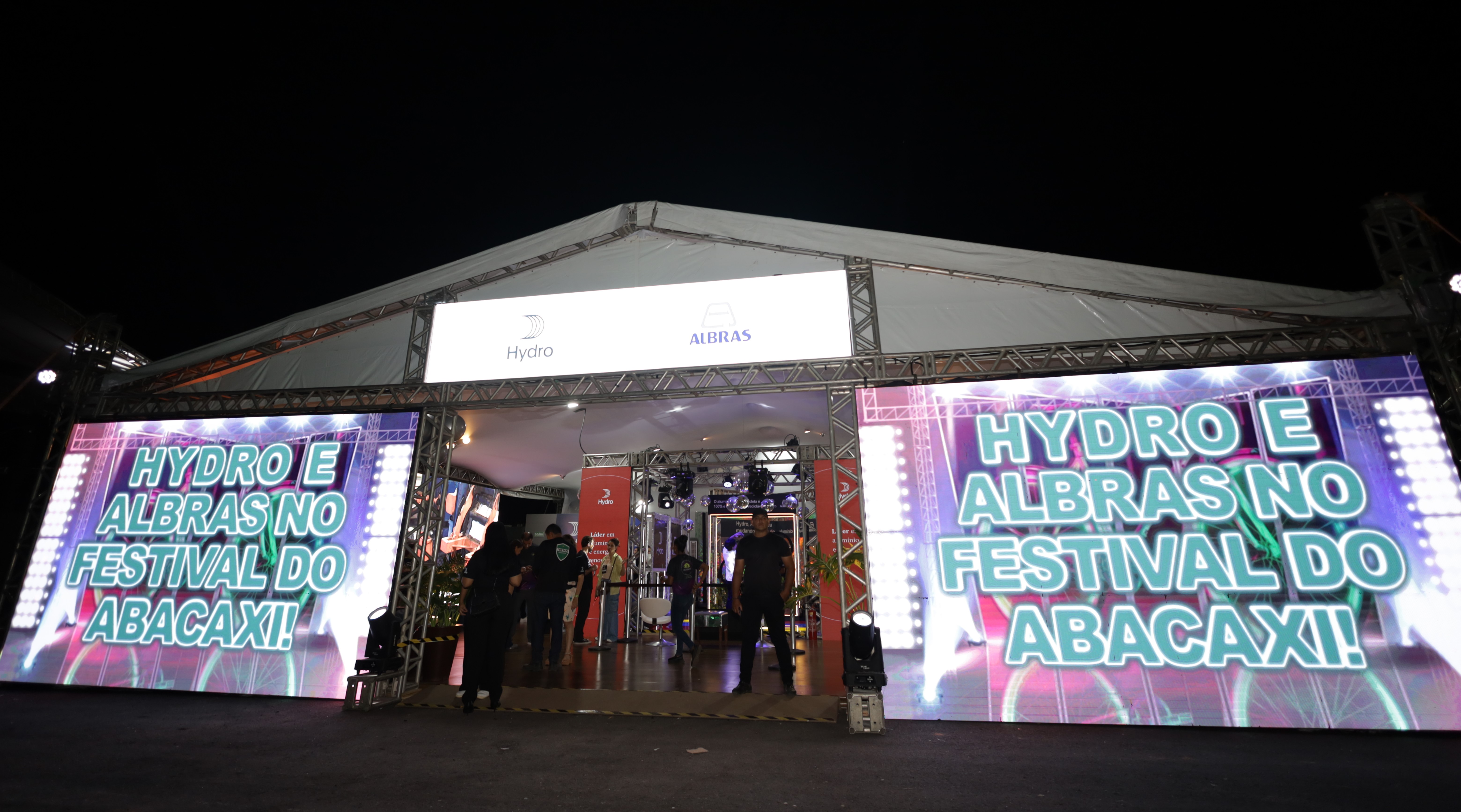 a group of people standing outside a building with neon signs