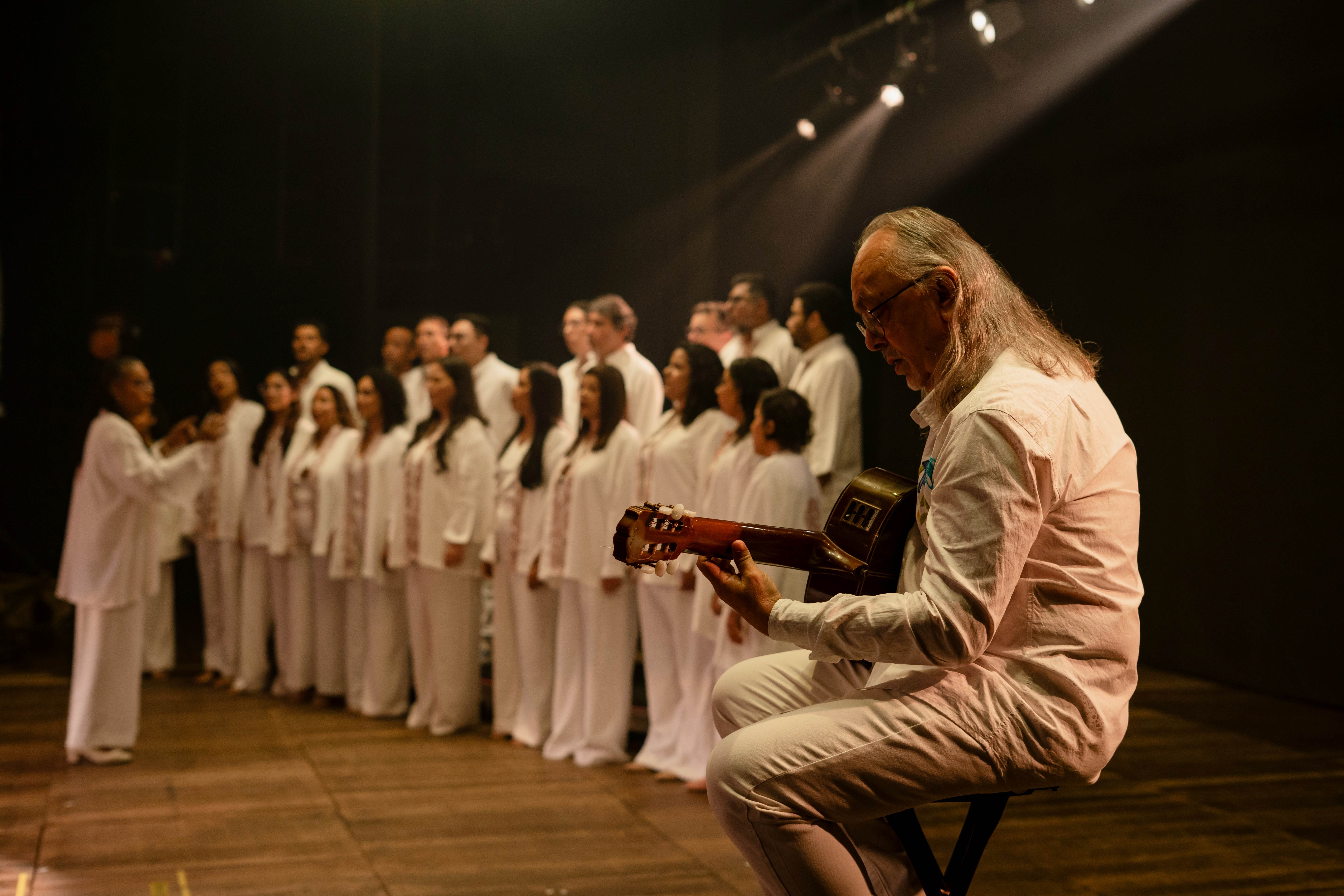 a man playing a violin in front of a group of people in white robes