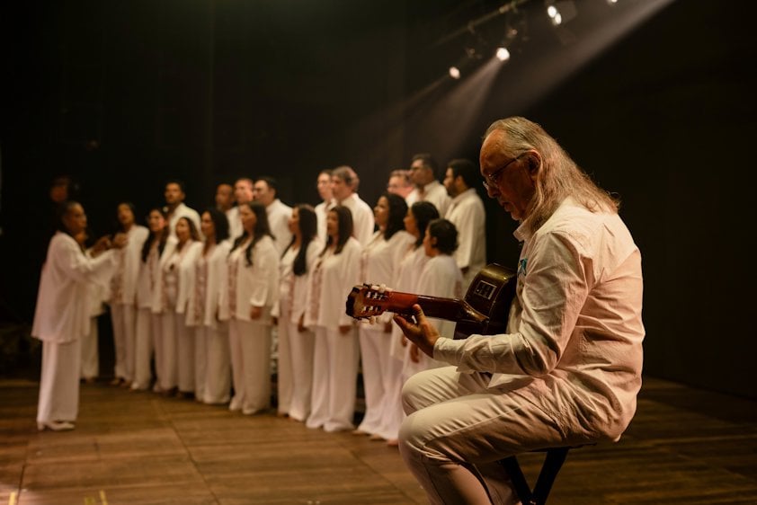 a man playing a violin in front of a group of people in white robes