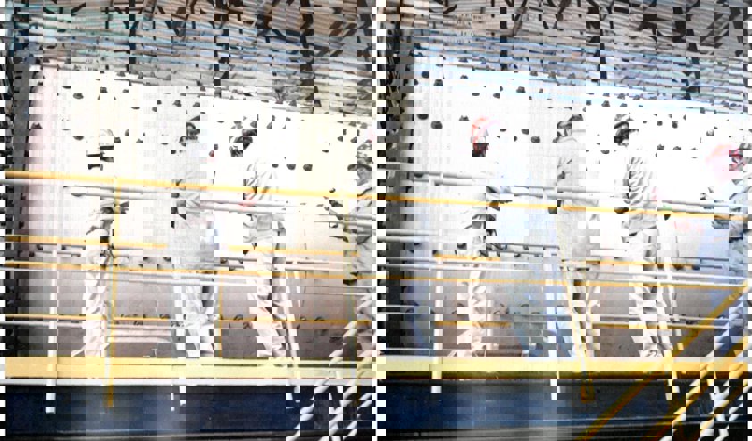 a group of people in white protective gear working on a metal frame