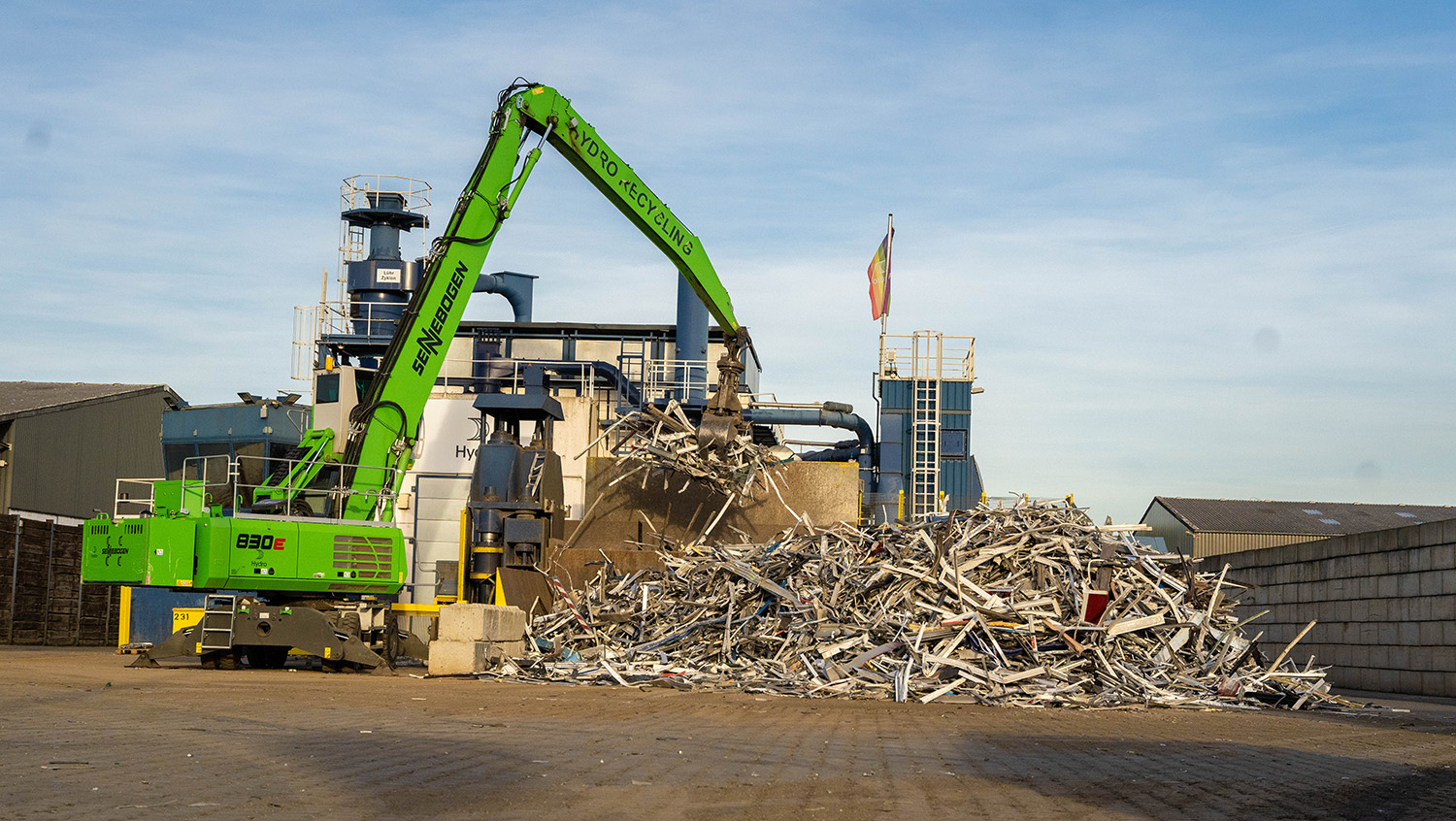 a green machine in front of a pile of scrap metal