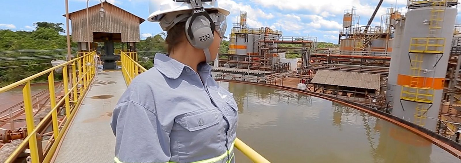 Alunorte's female employee stands watching the company's water treatment facility plant in the background