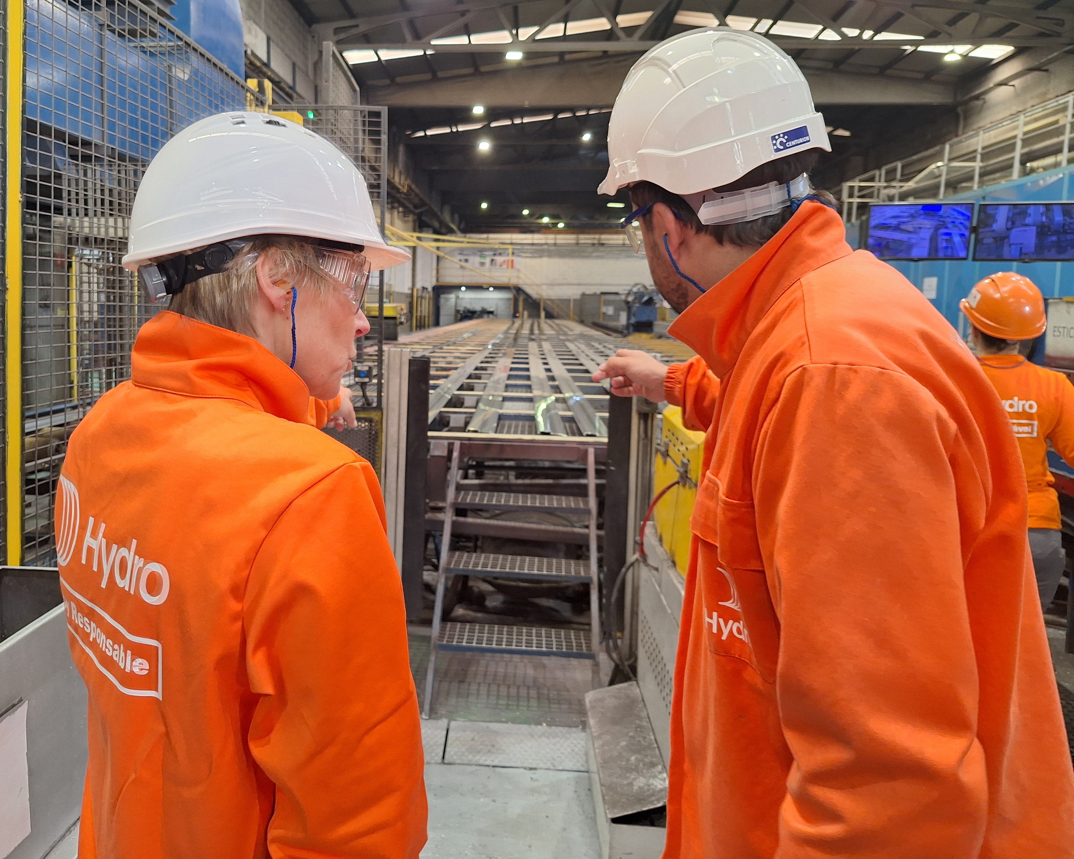 a group of people in orange vests looking at a machine