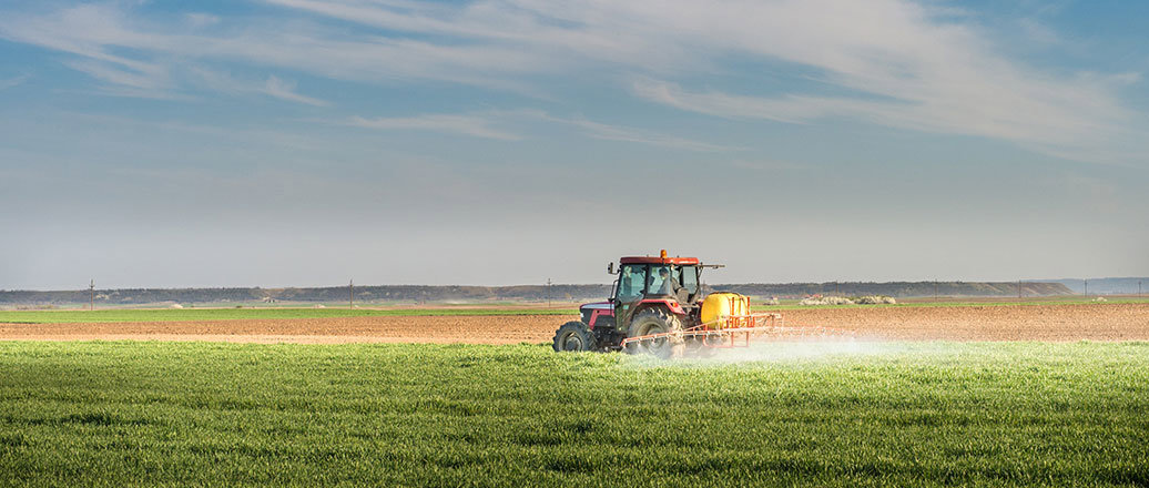 a tractor spraying a green field