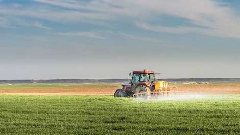 a tractor spraying a green field