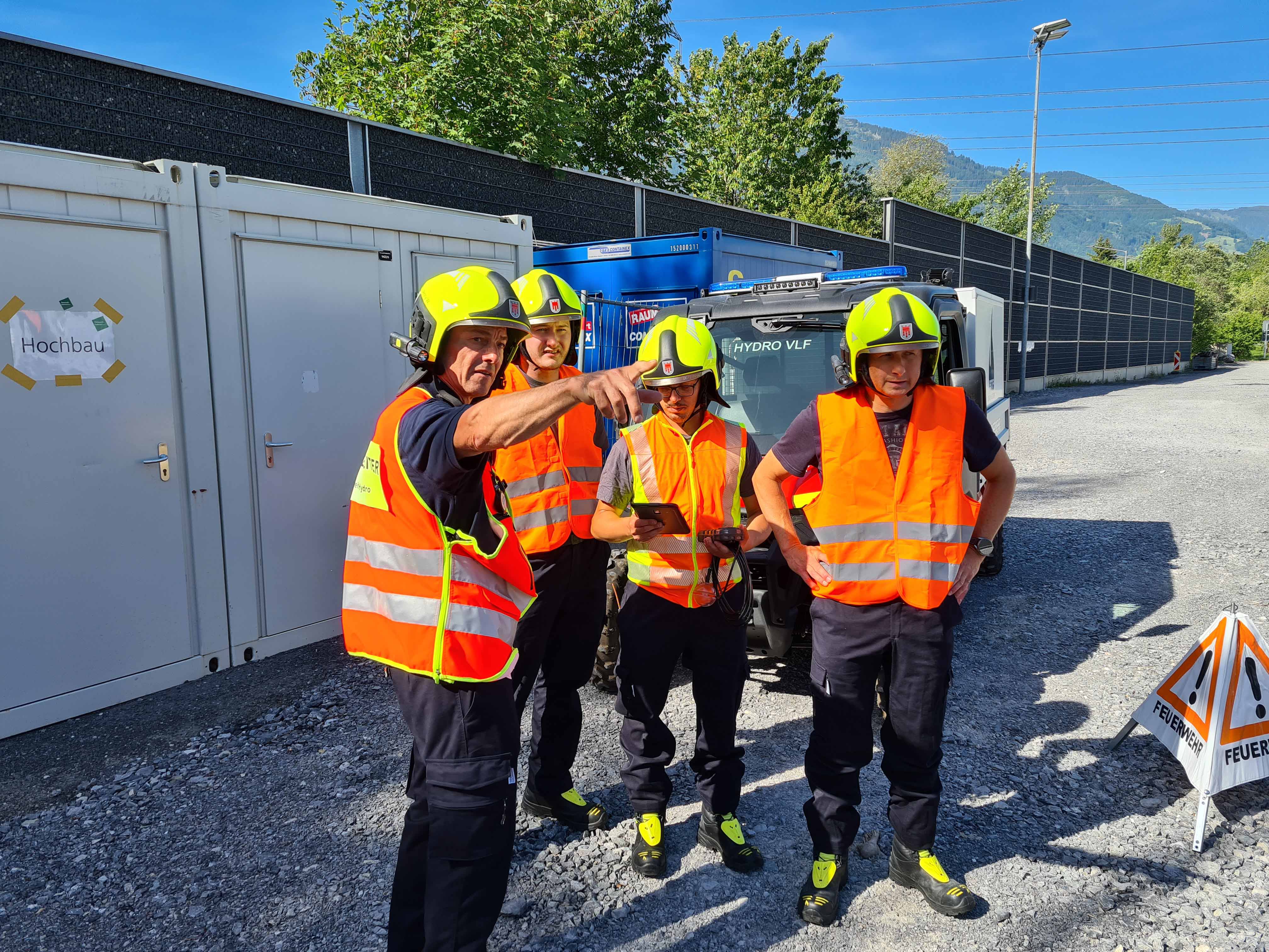 Vier Mitglieder der Betriebsfeuerwehr besprechen eine Übungssituation im Freien