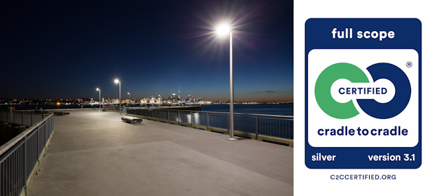 a walkway with a railing and a body of water with a city in the background