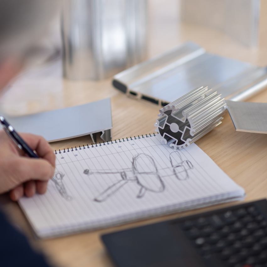 a hand holding a pen and a drawing on a piece of paper