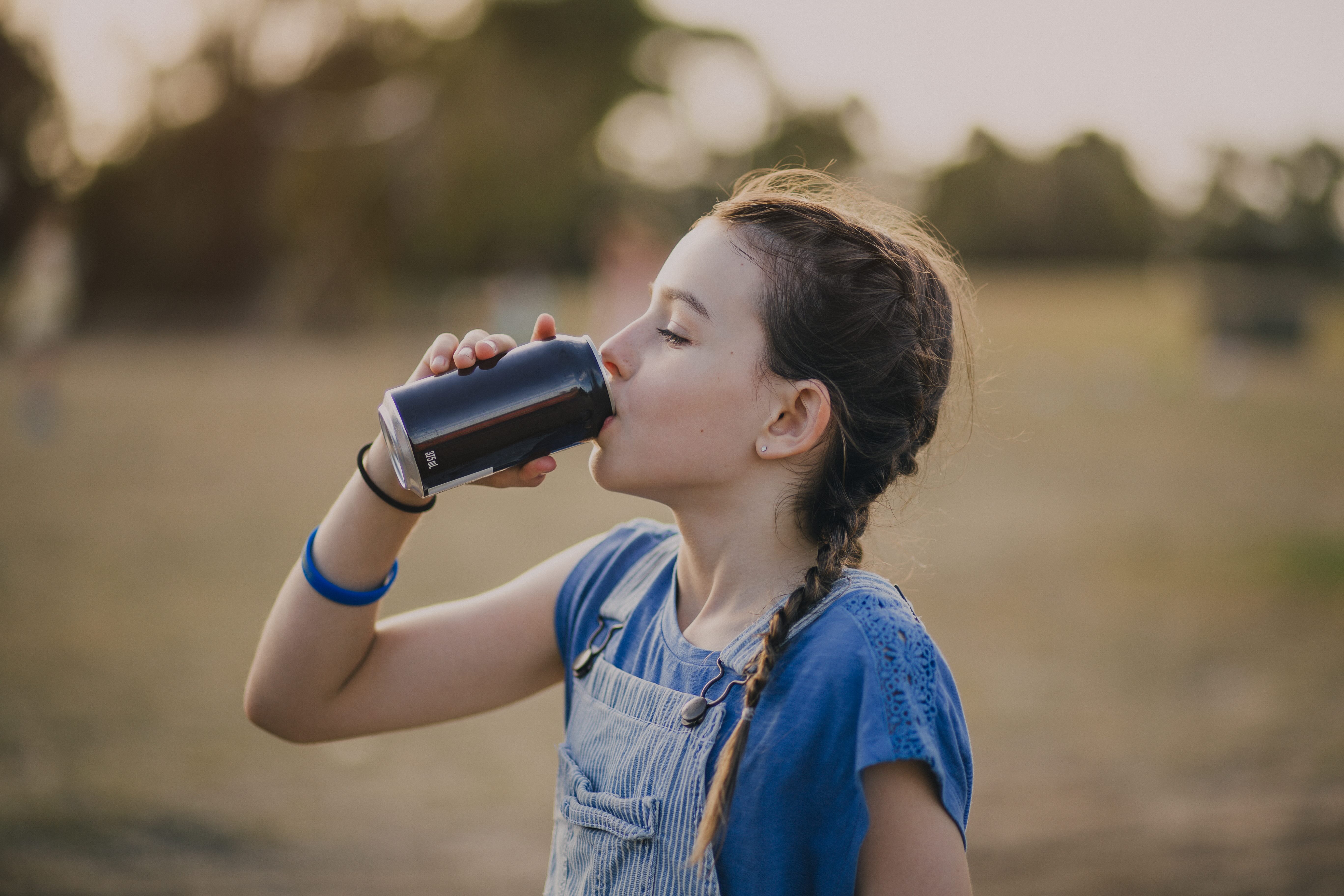 a girl drinking from a can