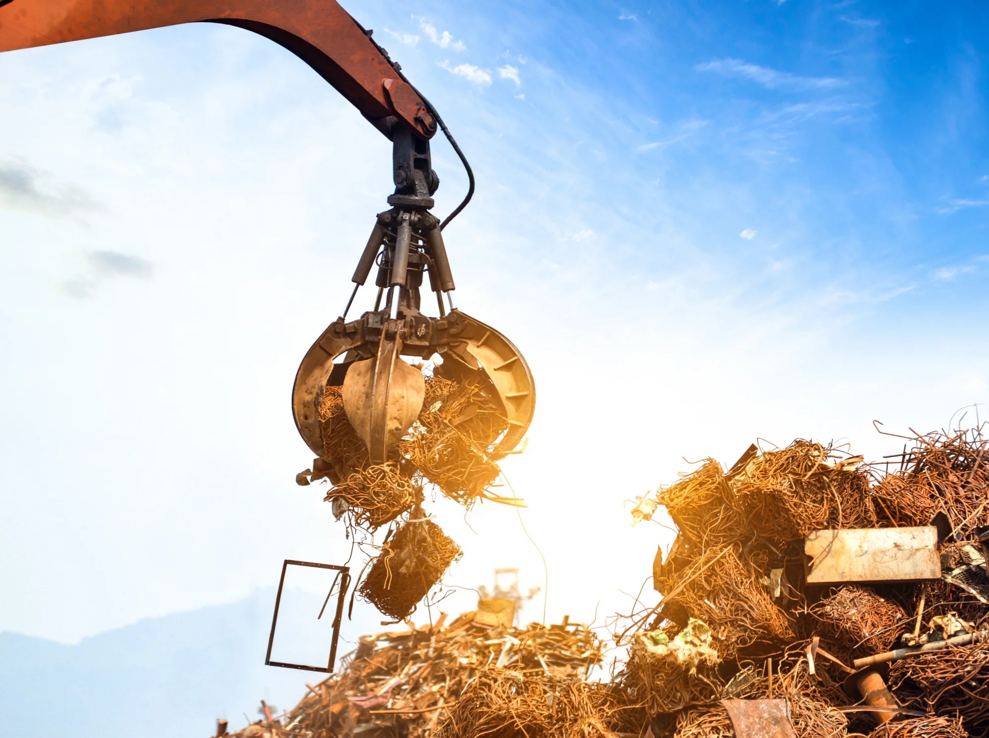 A crane lifting a pile of scrap material