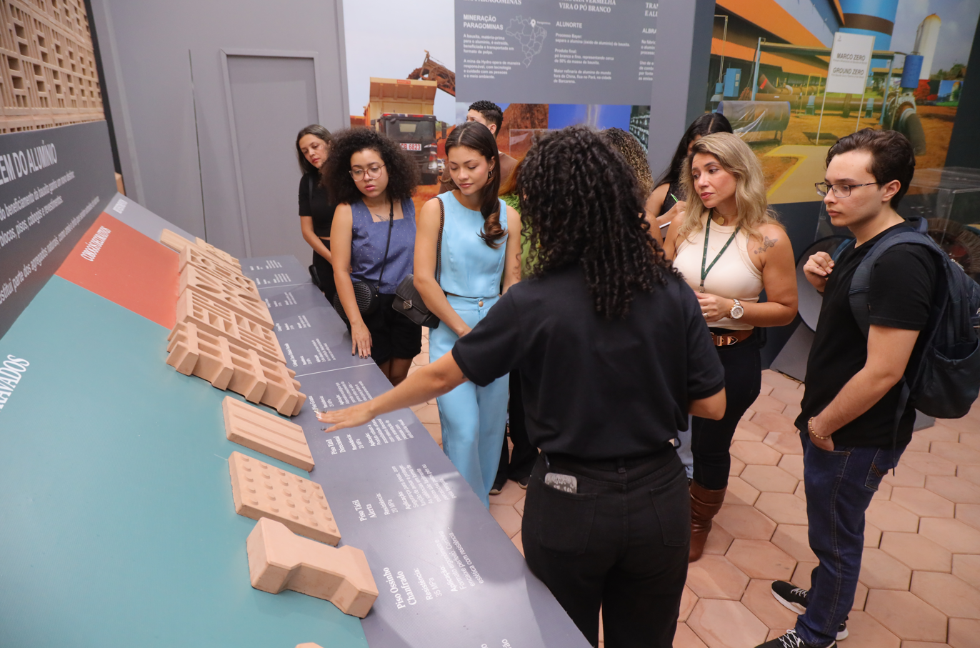 a group of people standing around a table with a model of a house
