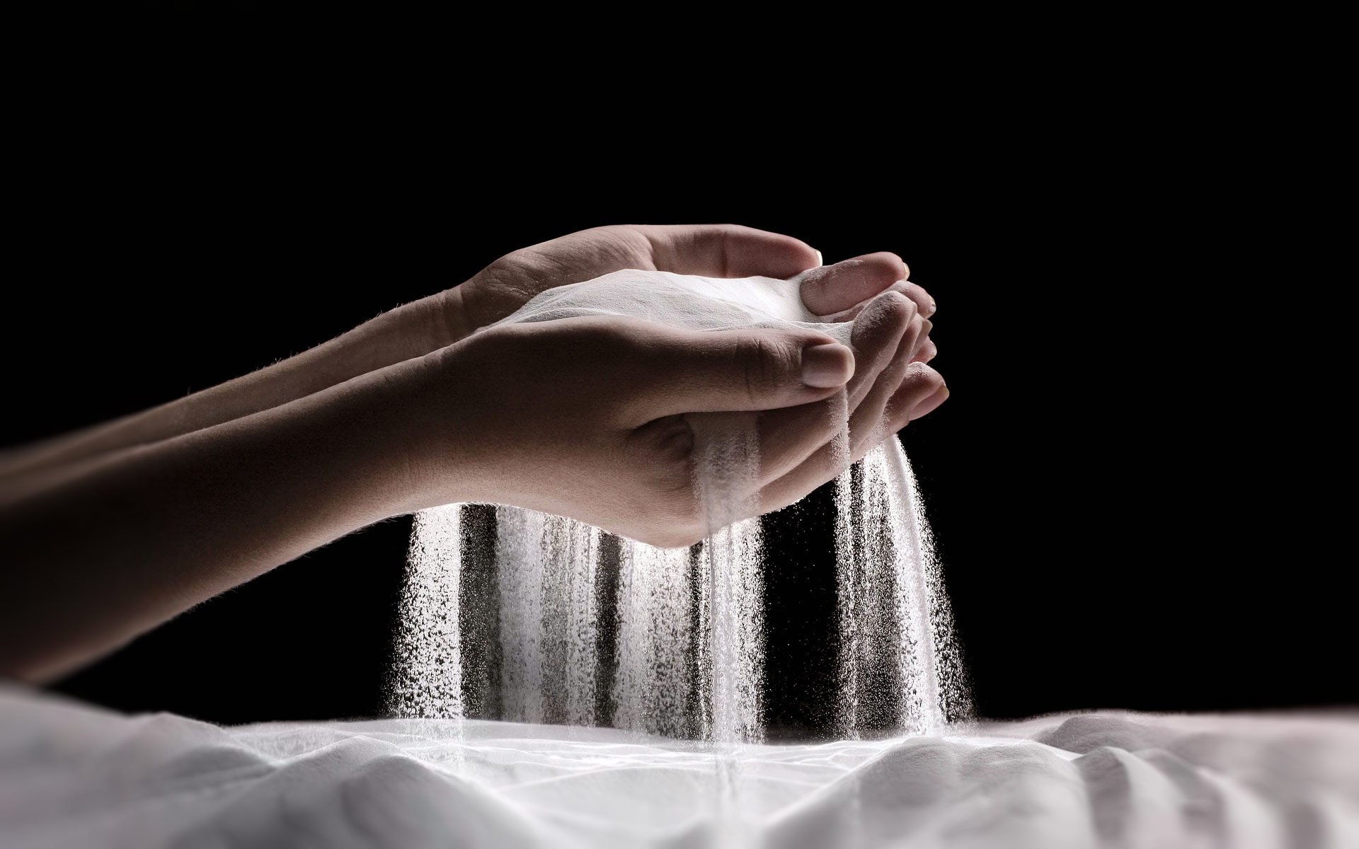 Hands holding a heap of white alumina powder