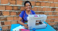 Costureira Angela Araújo sentada  com máquina de costura