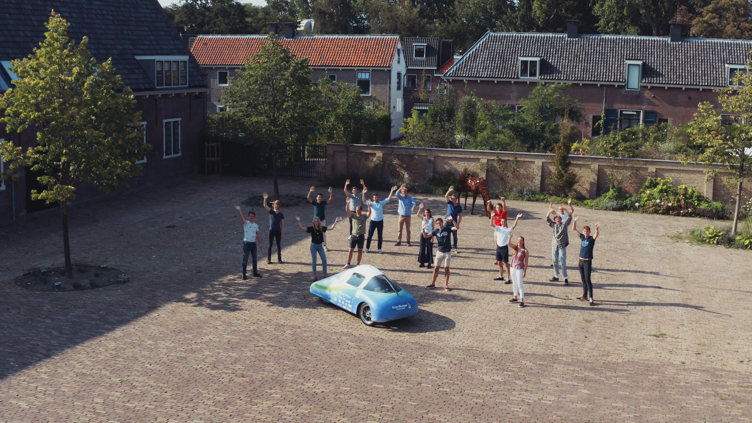 a group of people standing around a blue car