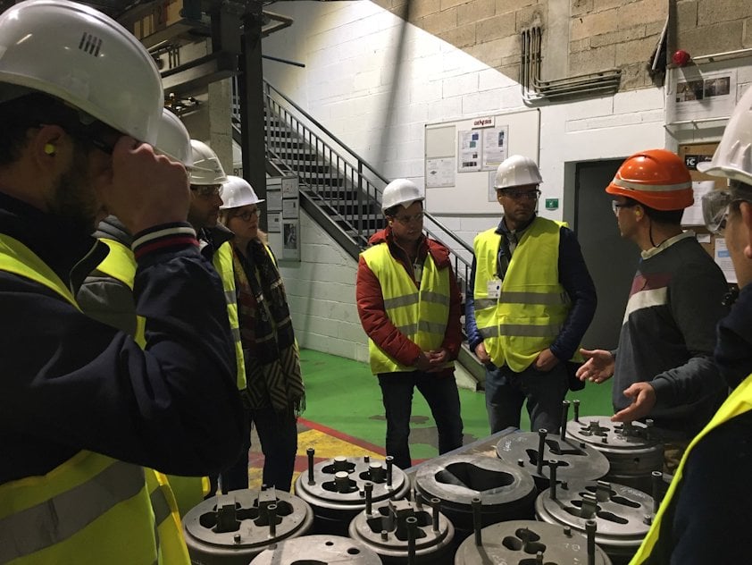a group of people wearing hardhats looking at a display of hats