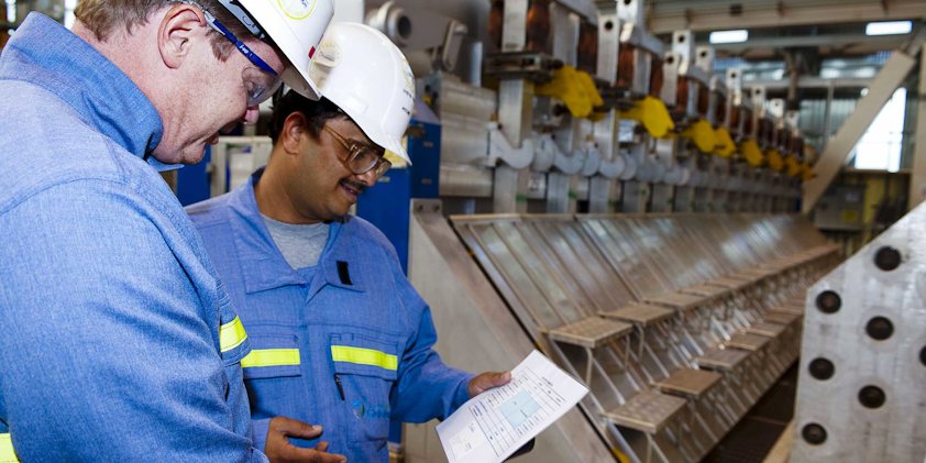 a couple of men in hard hats looking at a piece of paper