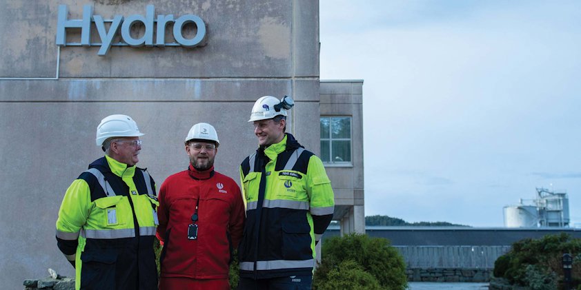 a group of men wearing hardhats and standing in front of a building