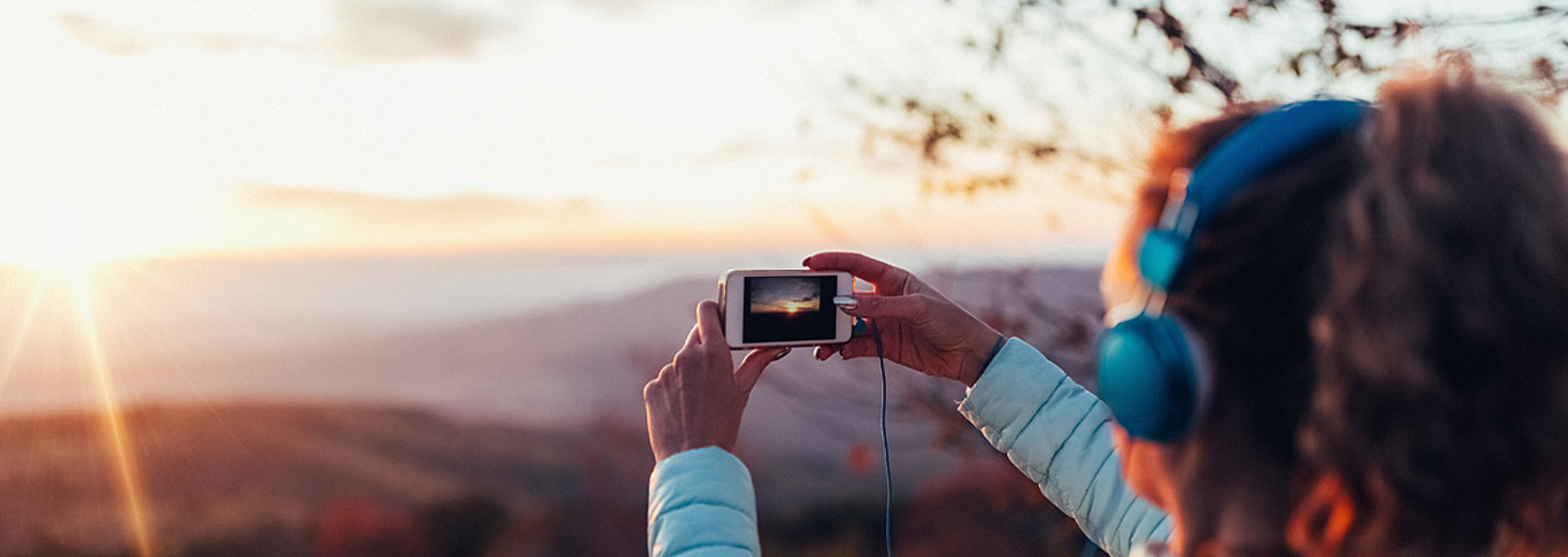 girl taking photo of sunset with smartphone