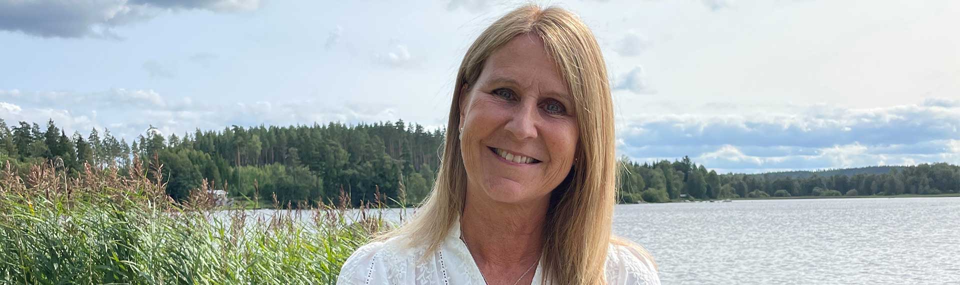 a person smiling in front of a lake