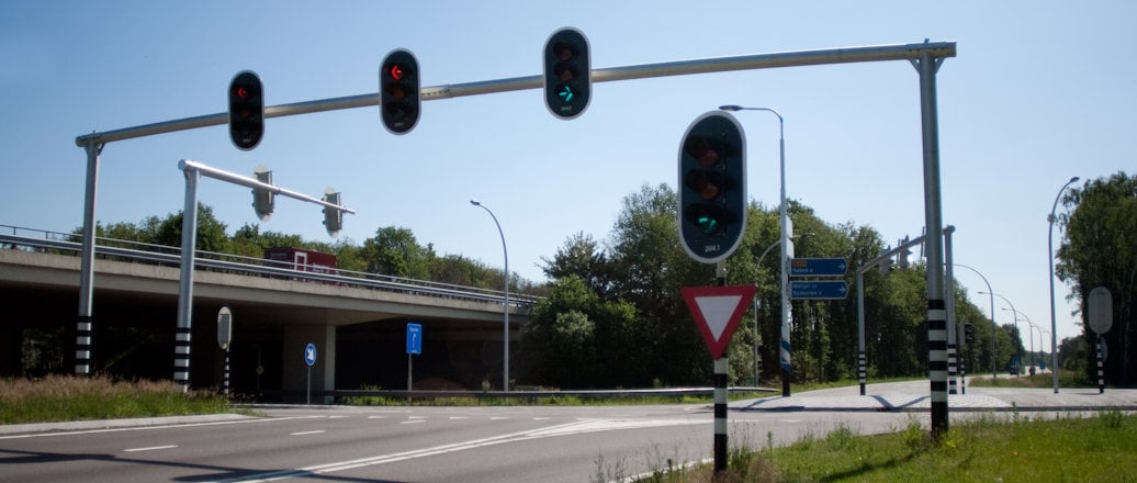 an intersection. traffic lights hanging on a pole across the road an intersection. traffic lights hanging on a pole across the road